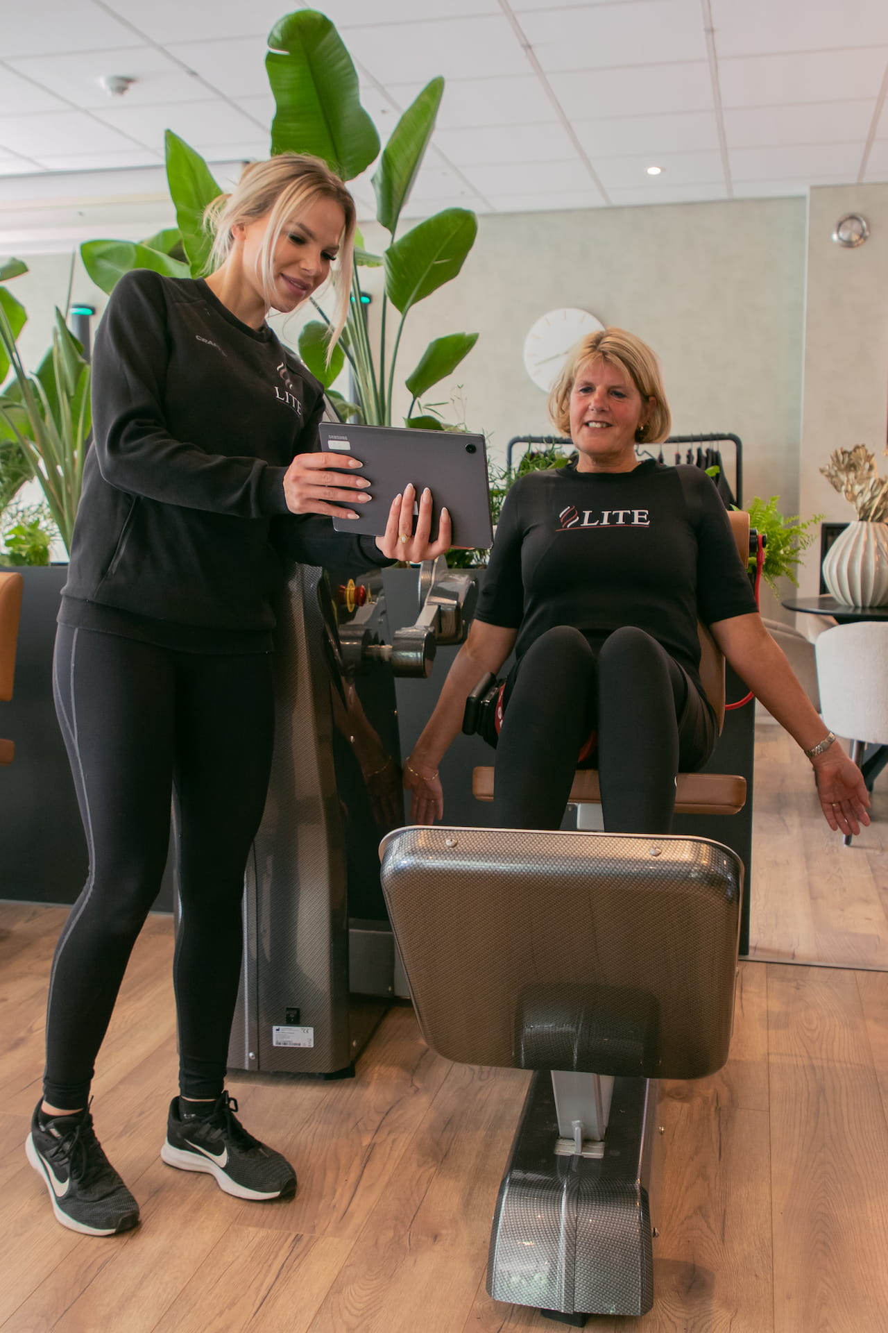 Een vrouw op een fitness apparaat met een vrouwelijke begeleider